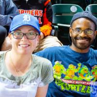 A man and woman smiling in the stands of Comerica Park